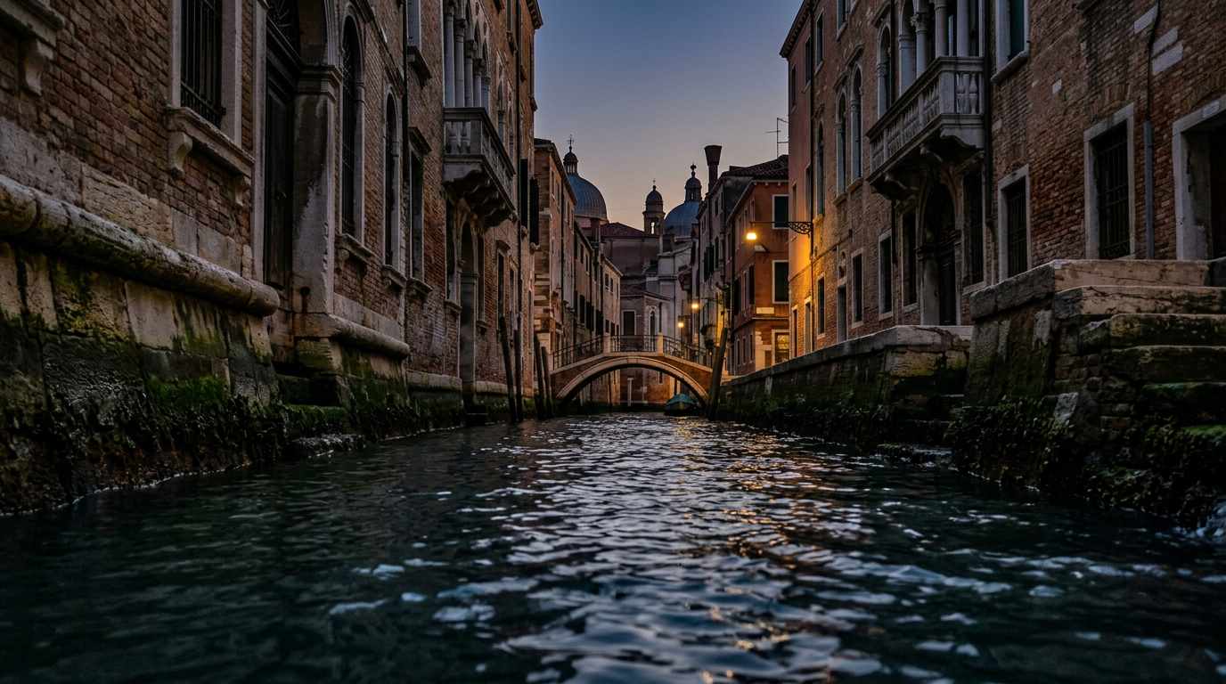 A moody, atmospheric view of a Venetian canal at dusk, showing the dark water reflecting ancient stone foundations and wooden mooring poles.